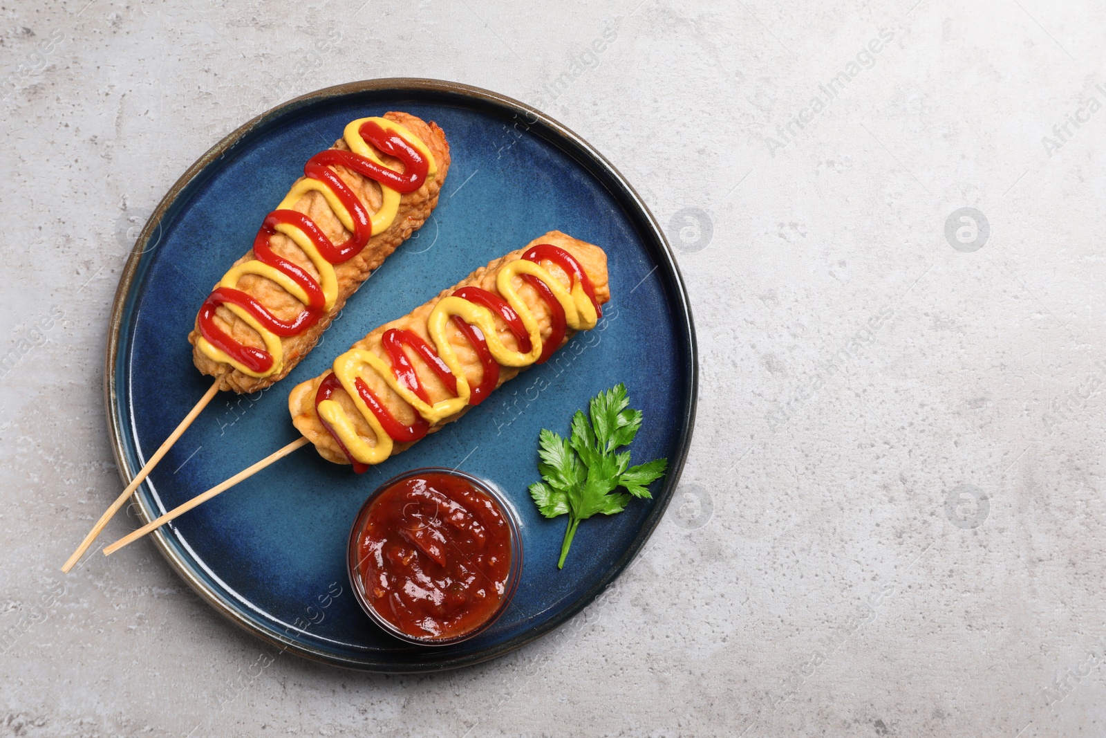 Photo of Delicious corn dogs with mustard and ketchup served on light table, top view