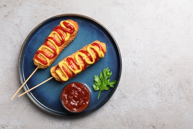 Delicious corn dogs with mustard and ketchup served on light table, top view