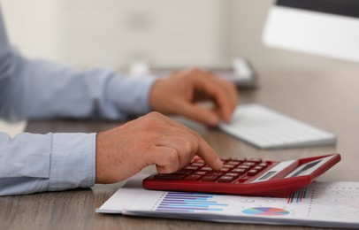 Photo of Professional accountant using calculator at wooden desk, closeup