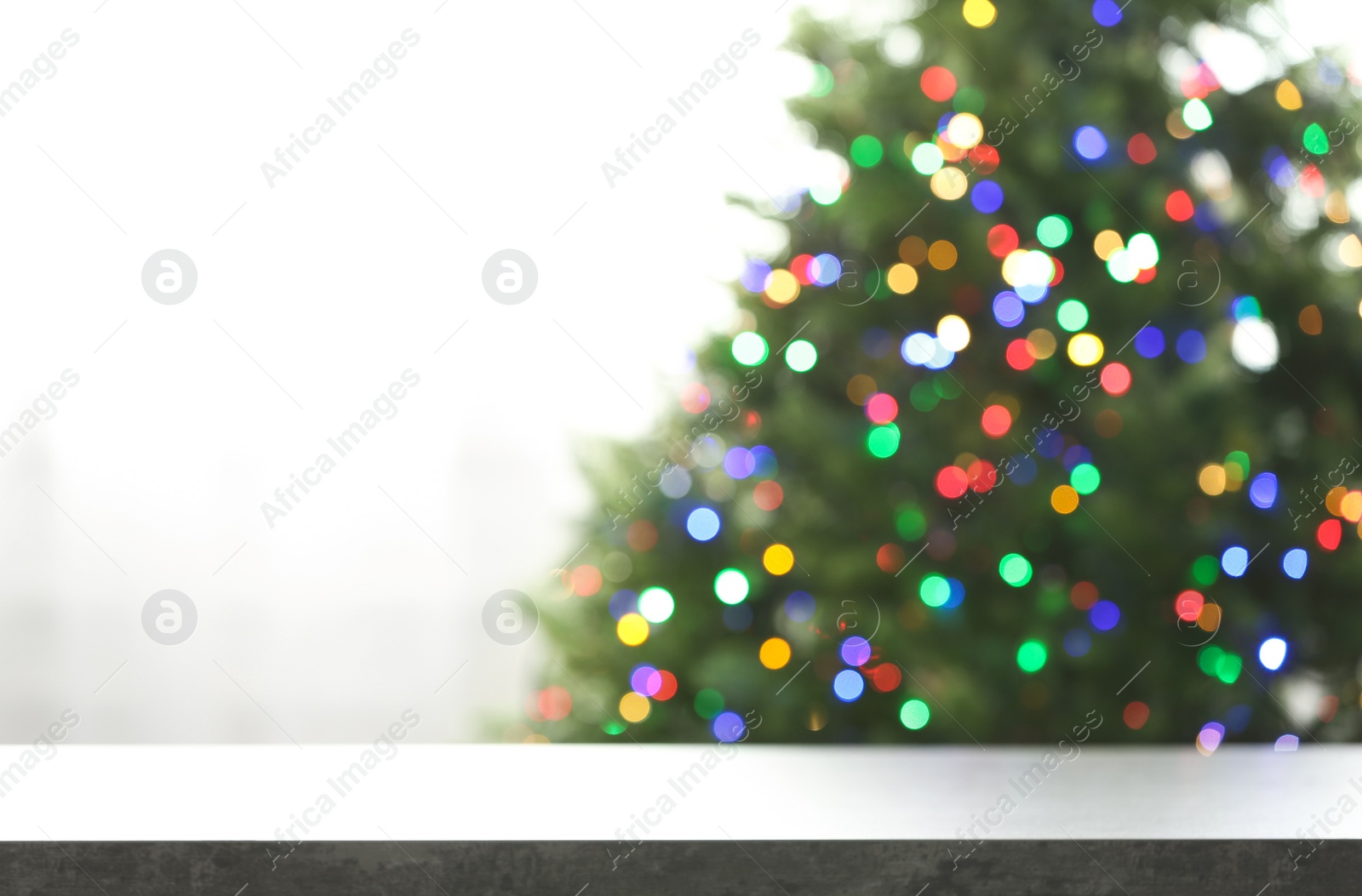 Photo of Empty table and blurred fir tree with colorful Christmas lights on background, bokeh effect. Space for design