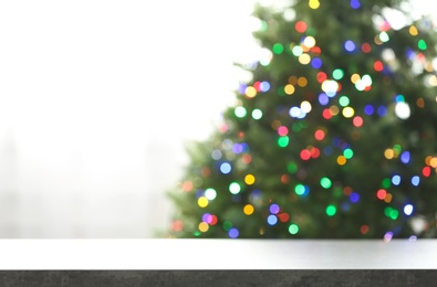 Photo of Empty table and blurred fir tree with colorful Christmas lights on background, bokeh effect. Space for design