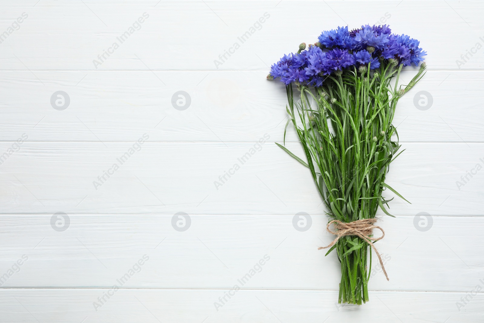 Photo of Bouquet of beautiful cornflowers on white wooden table, top view. Space for text