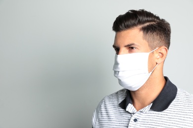 Photo of Man in protective face mask on light grey background. Space for text