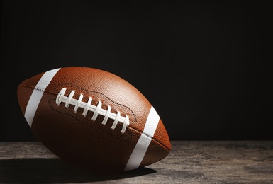 Photo of New American football ball on table against dark background