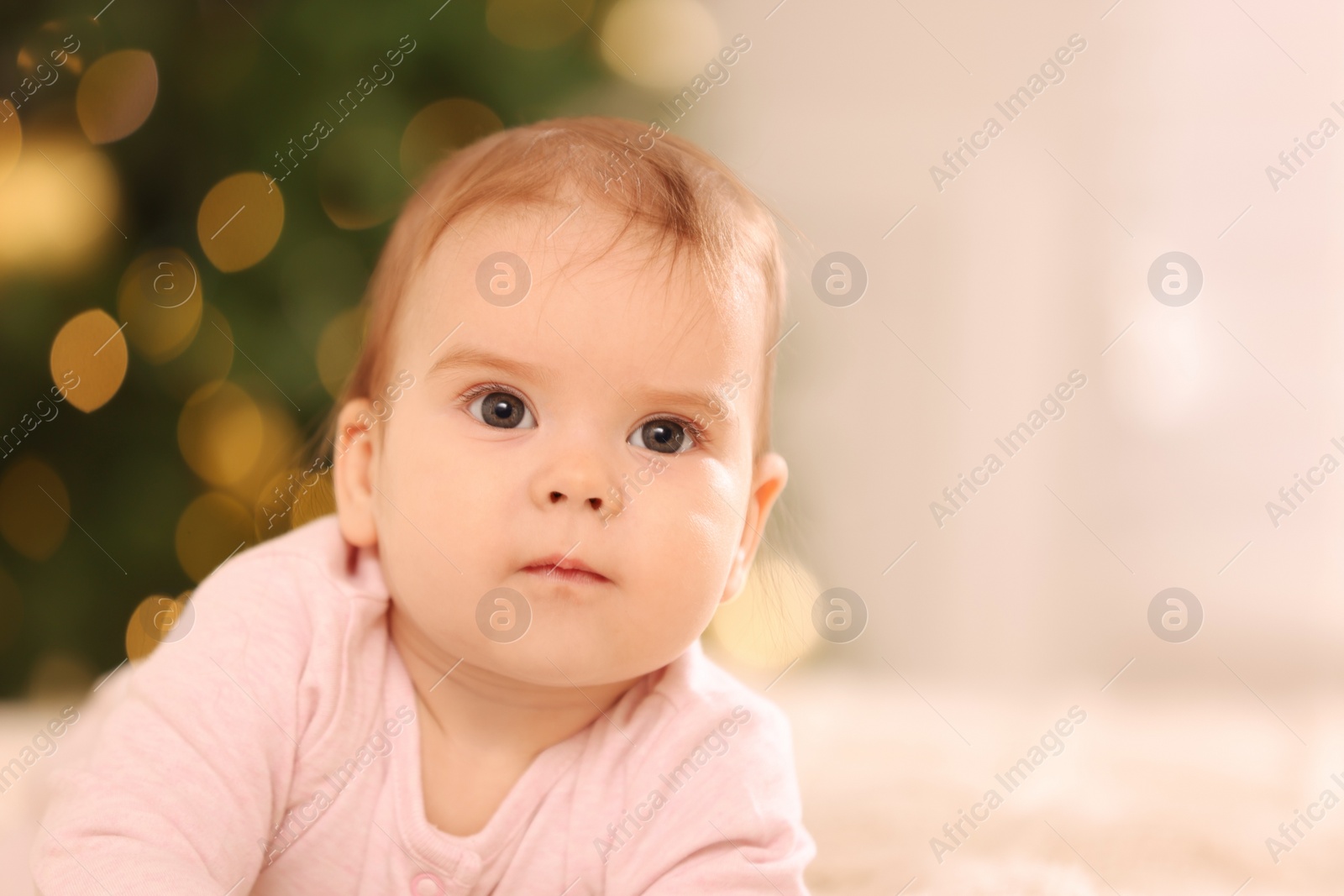 Photo of Portrait of cute little baby against blurred festive lights, space for text. Winter holiday