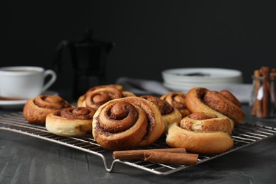 Tasty cinnamon rolls on black table, space for text