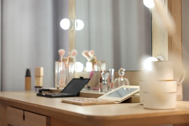 Cosmetic products on wooden dressing table in makeup room