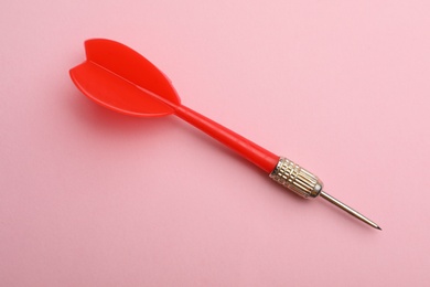 Photo of Red dart arrow on pink background, top view