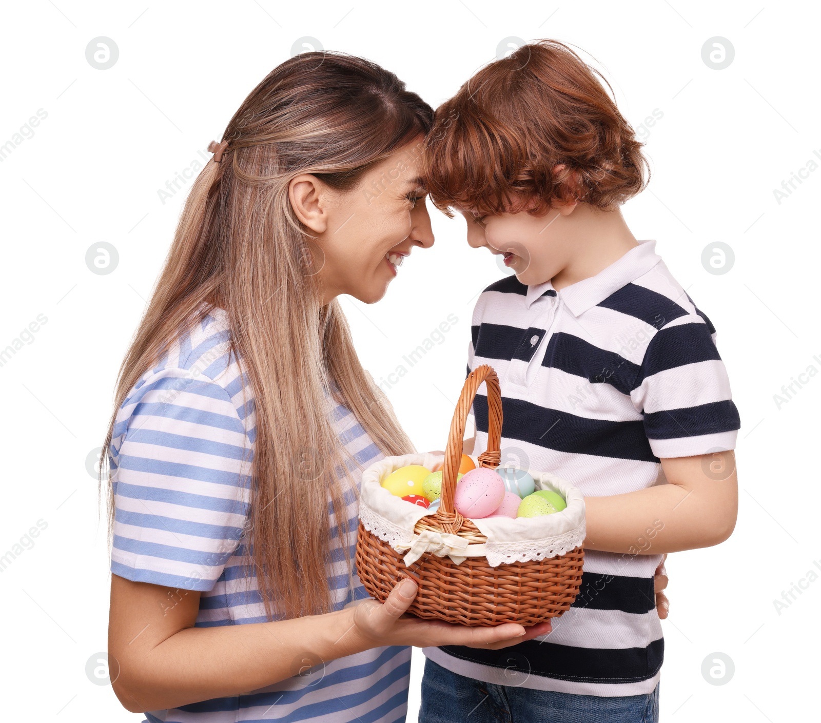 Photo of Easter celebration. Happy mother and her cute little son with wicker basket full of painted eggs isolated on white