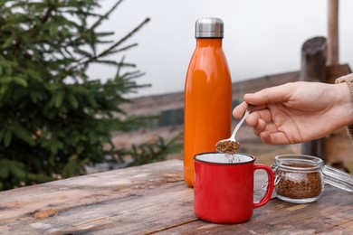 Photo of Woman making instant coffee at wooden table outdoors, closeup