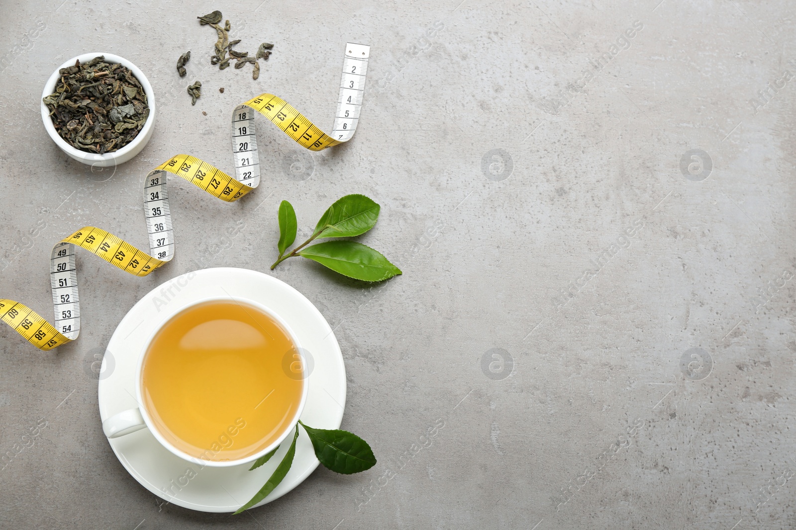 Photo of Flat lay composition with herbal diet tea and measuring tape on light table. Space for text