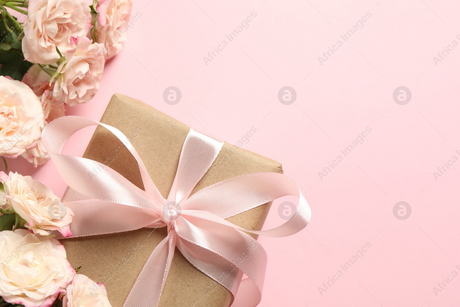 Photo of Happy Mother's Day. Beautiful roses and gift box on pink background, flat lay. Space for text