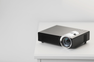 Photo of Modern video projector on white table indoors. Space for text