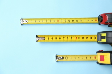 Photo of Tapes measure on light blue background, flat lay. Construction tool