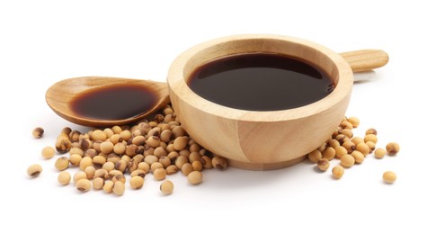 Tasty soy sauce in bowl, soybeans and spoon isolated on white