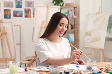 Photo of Beautiful young woman painting in studio. Creative hobby