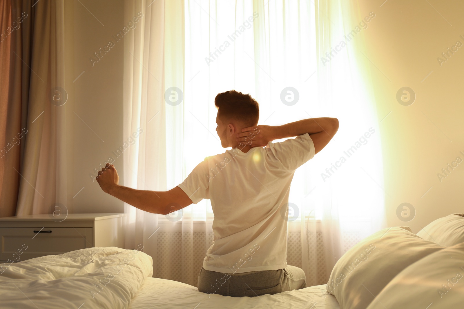 Photo of Young man stretching on bed at home. Lazy morning