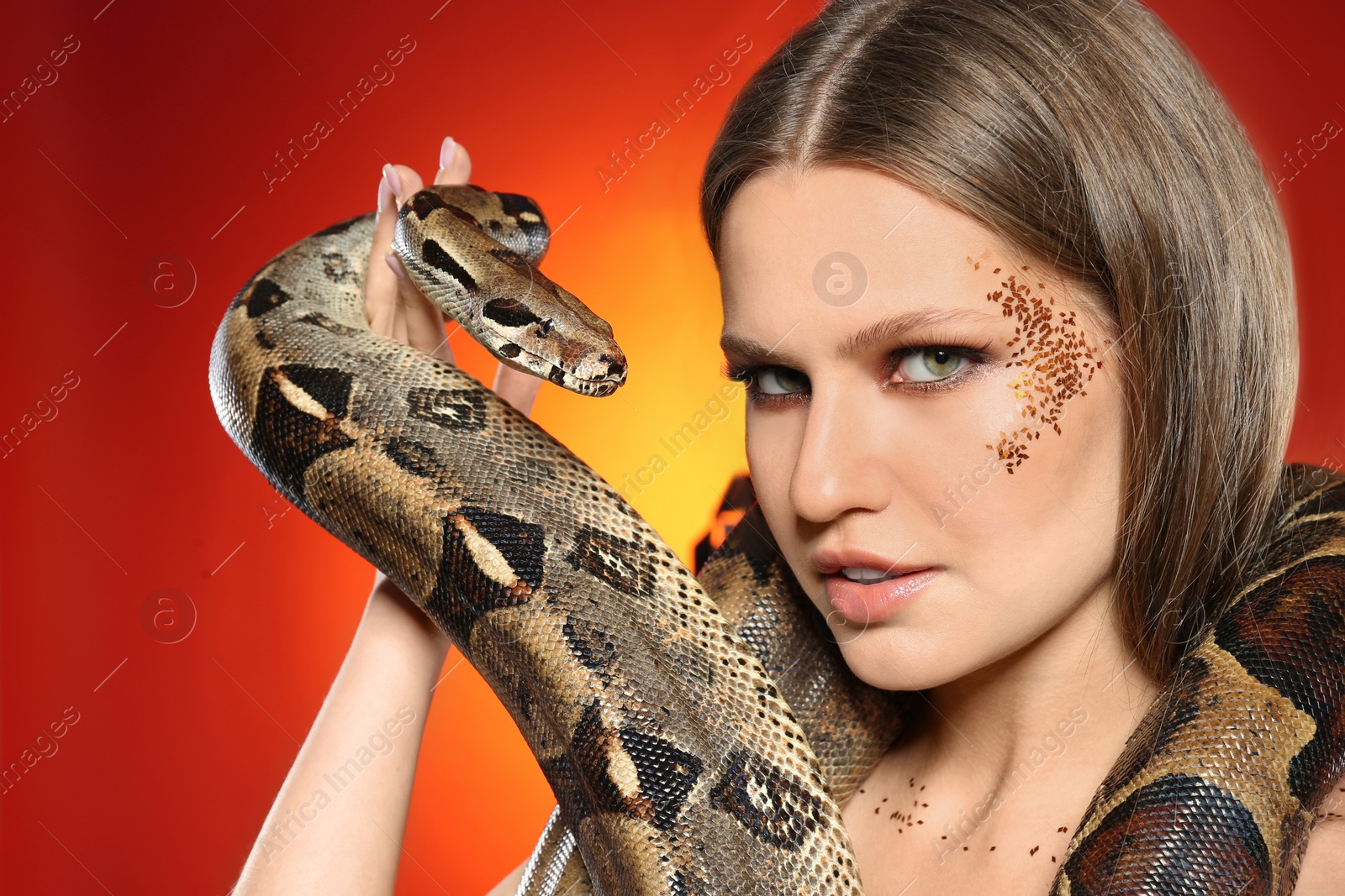 Photo of Beautiful woman with boa constrictor on bright colorful background, closeup