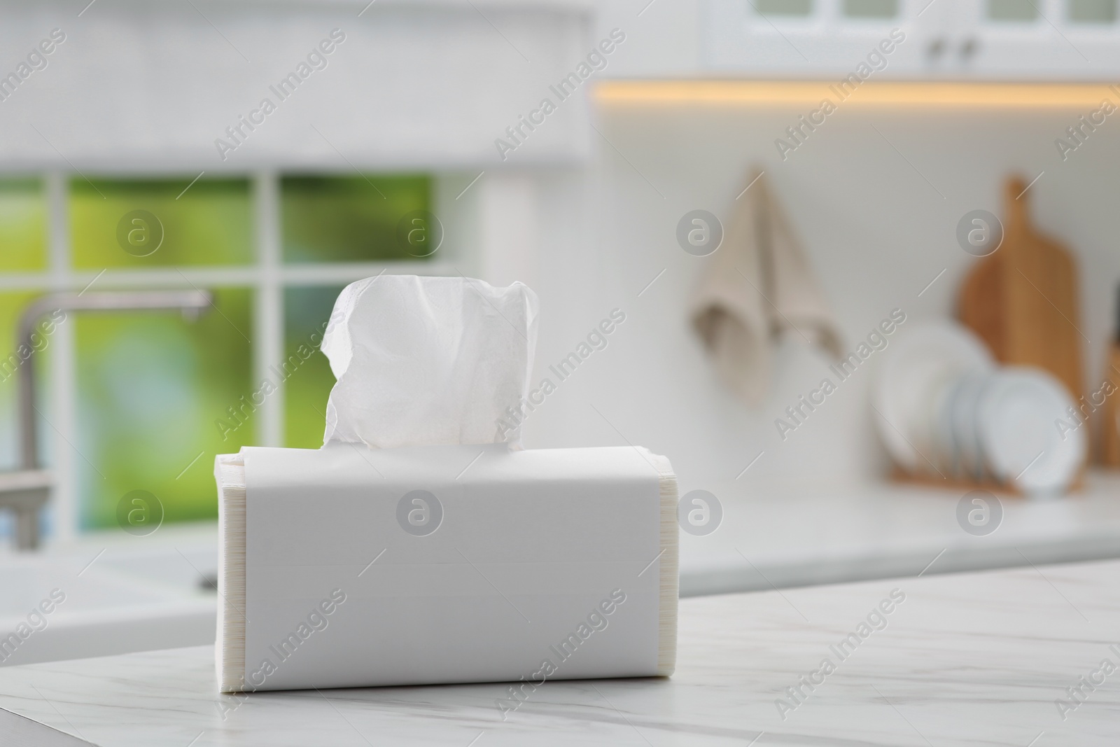 Photo of Package of paper towels on white table in kitchen. Space for text