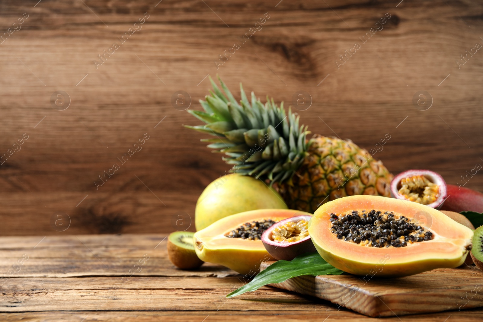 Photo of Fresh ripe papaya and other fruits on wooden table. Space for text