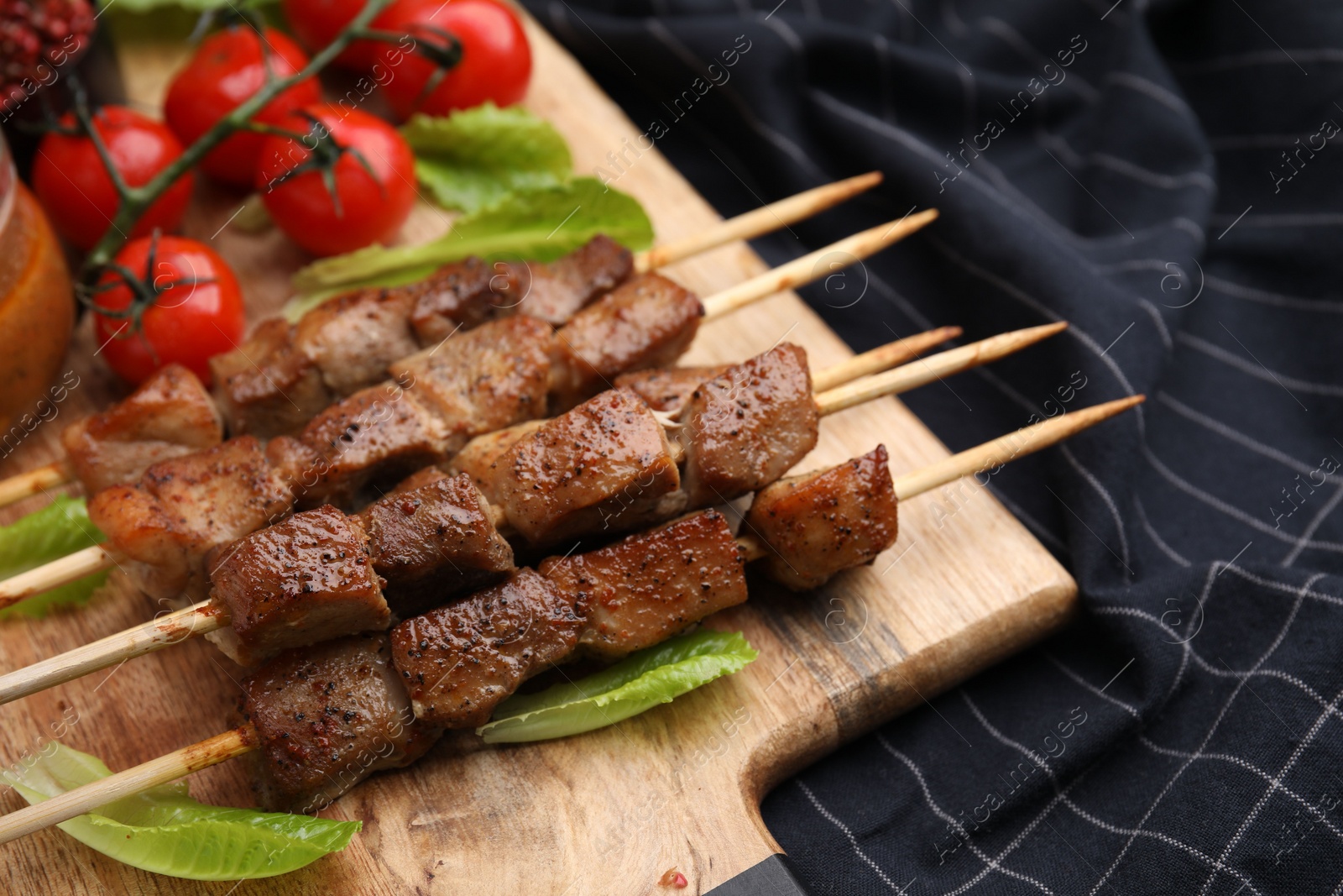 Photo of Tasty cooked marinated meat served with sauce and tomatoes on table, closeup