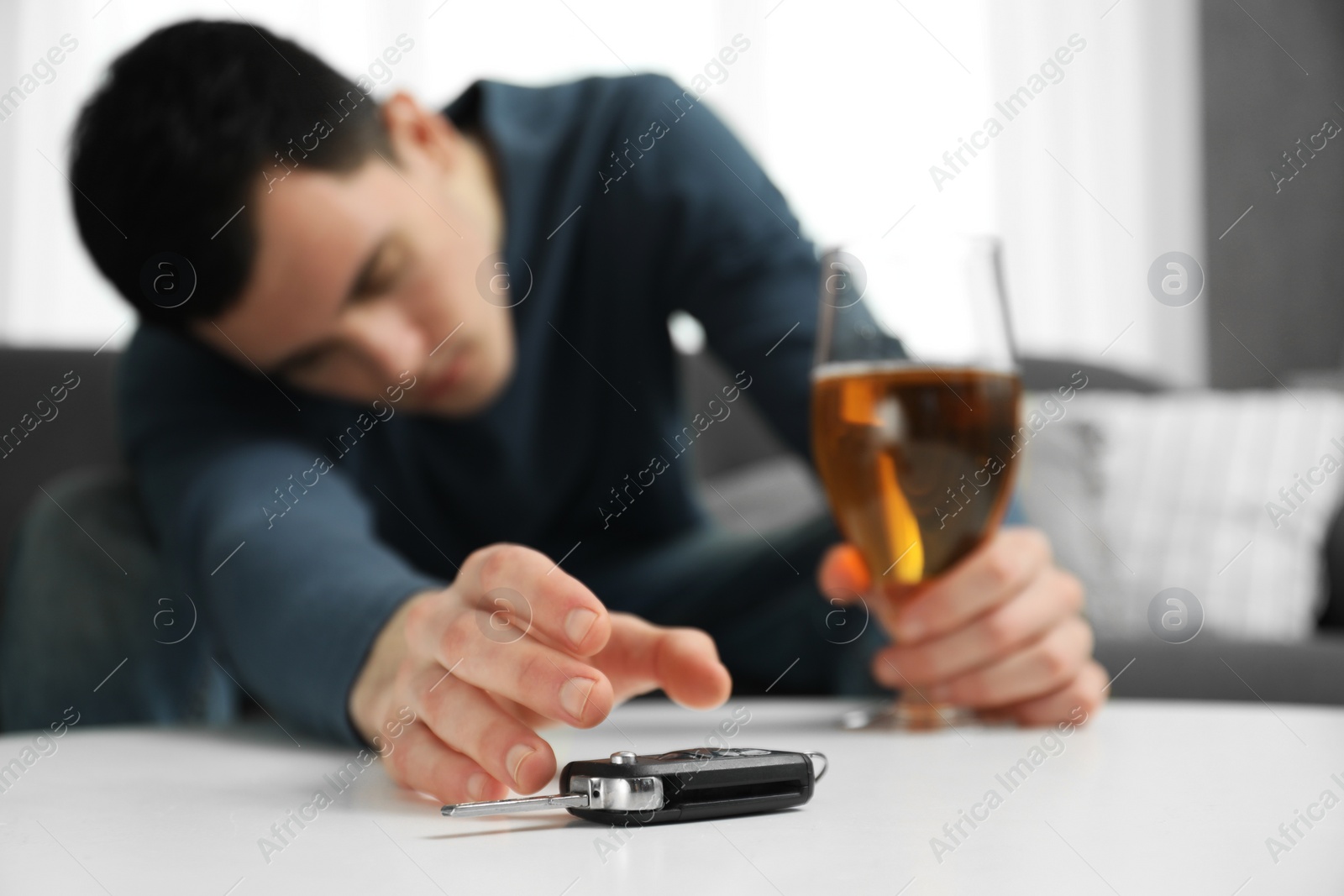 Photo of Drunk man reaching for car keys indoors, selective focus. Don't drink and drive concept