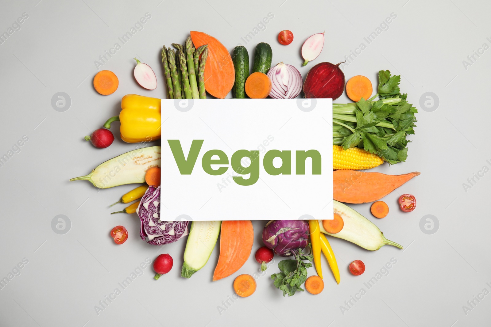 Image of Paper card with word Vegan and fresh vegetables on white background, flat lay