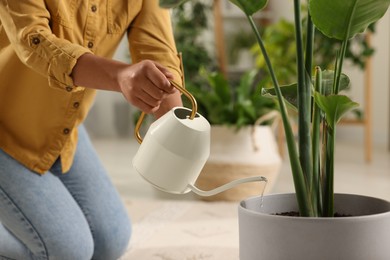 Woman watering beautiful potted houseplant indoors, closeup