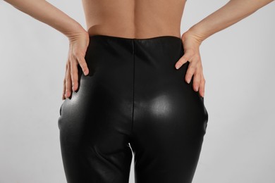 Photo of Woman in sexy black leather pants on light background, closeup