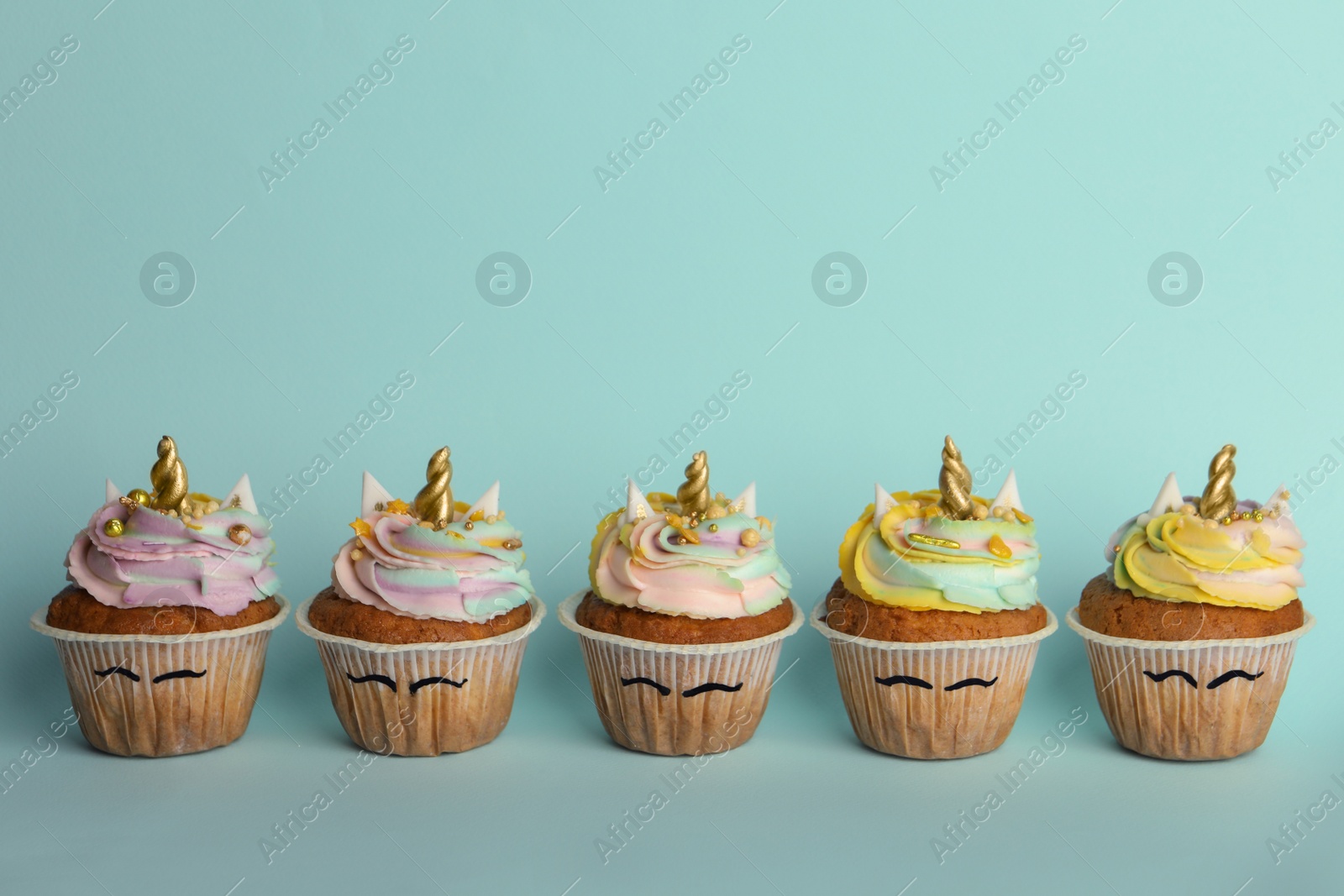 Photo of Many cute sweet unicorn cupcakes on light turquoise background, space for text