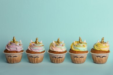 Photo of Many cute sweet unicorn cupcakes on light turquoise background, space for text