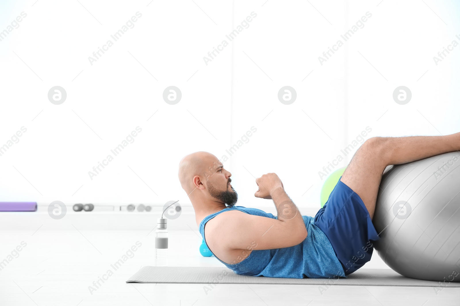 Photo of Overweight man doing exercise with fitness ball in gym