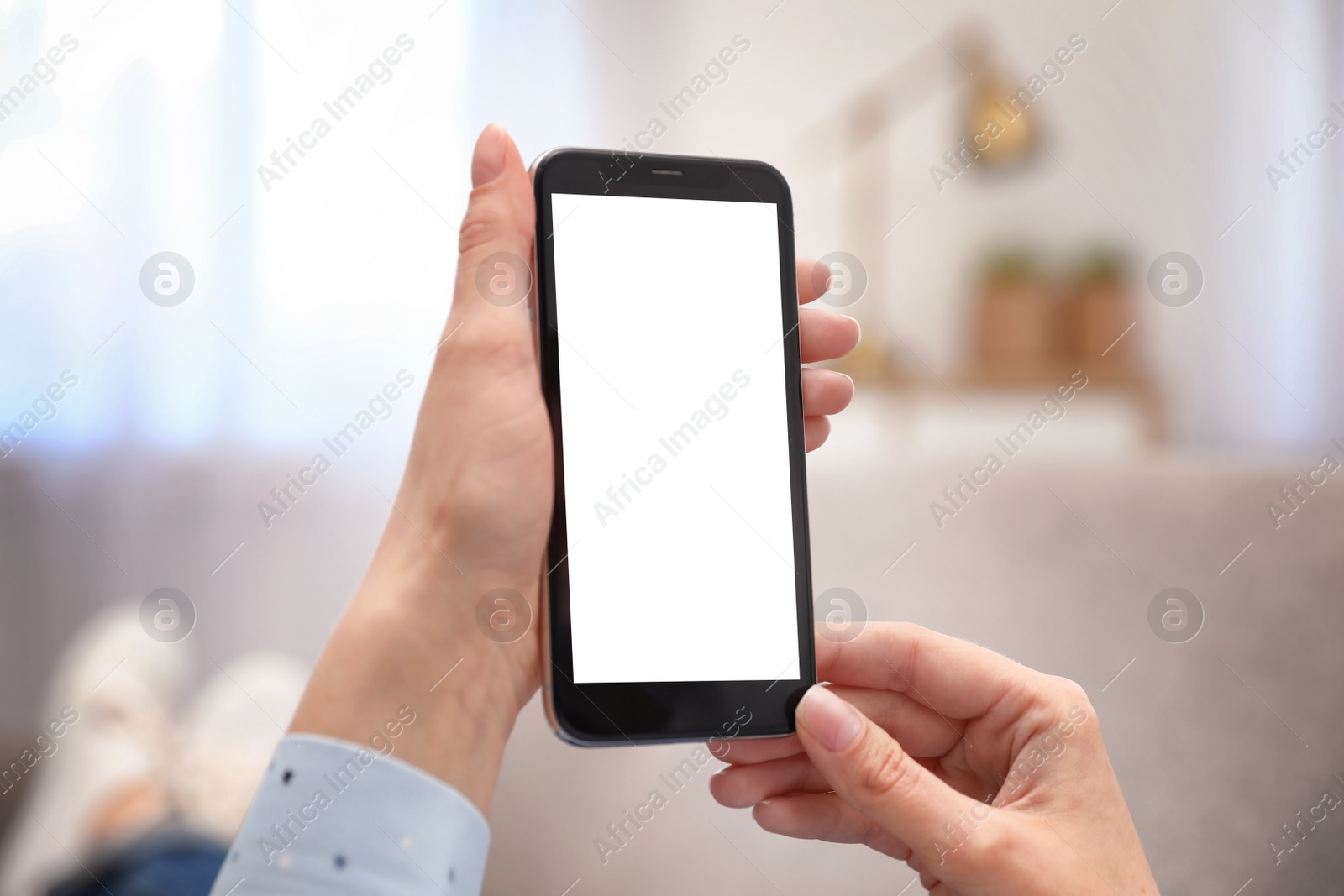 Photo of Woman holding smartphone with blank screen indoors, closeup of hands. Space for text