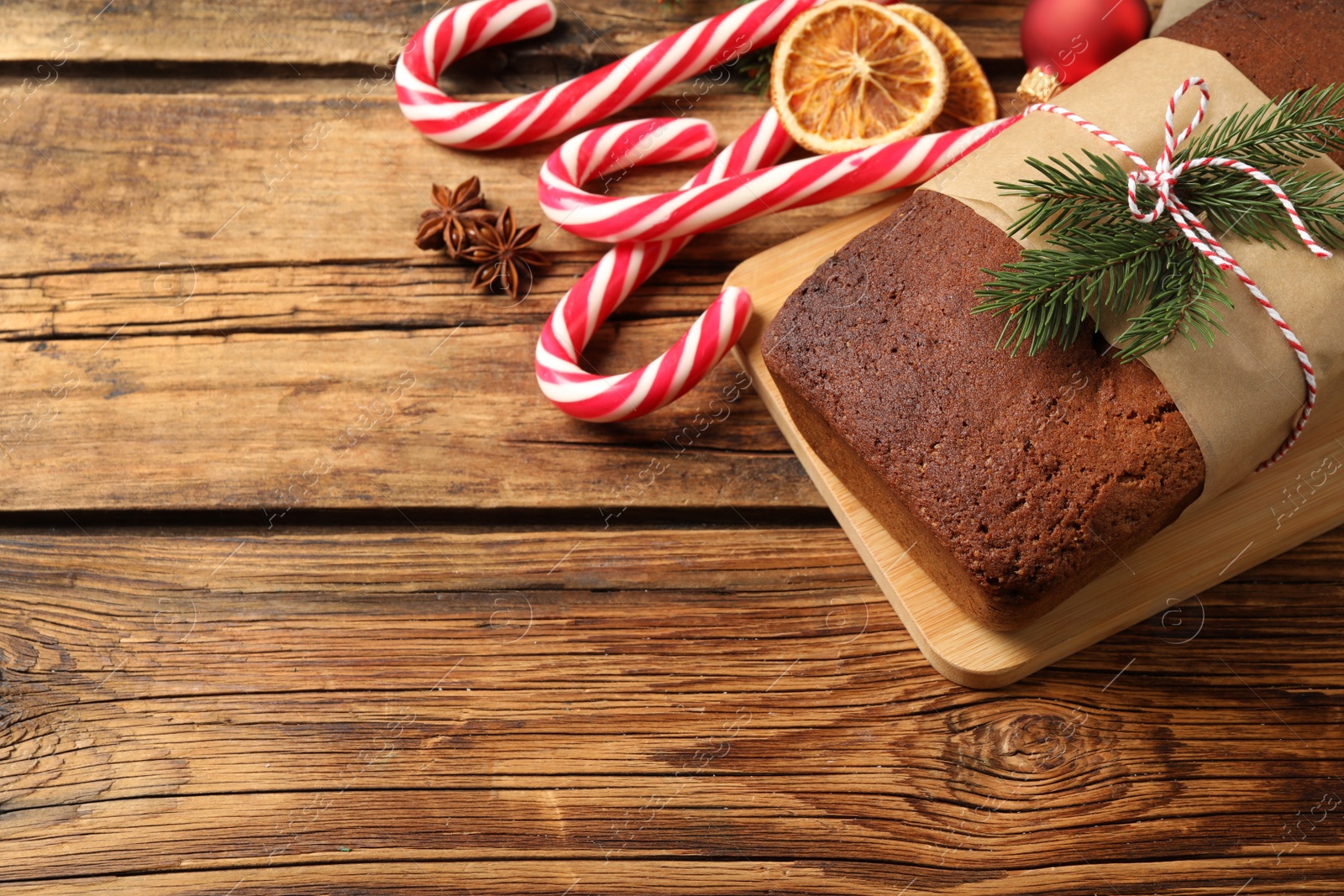 Photo of Delicious gingerbread cake, candy canes and Christmas decor on wooden table, above view. Space for text