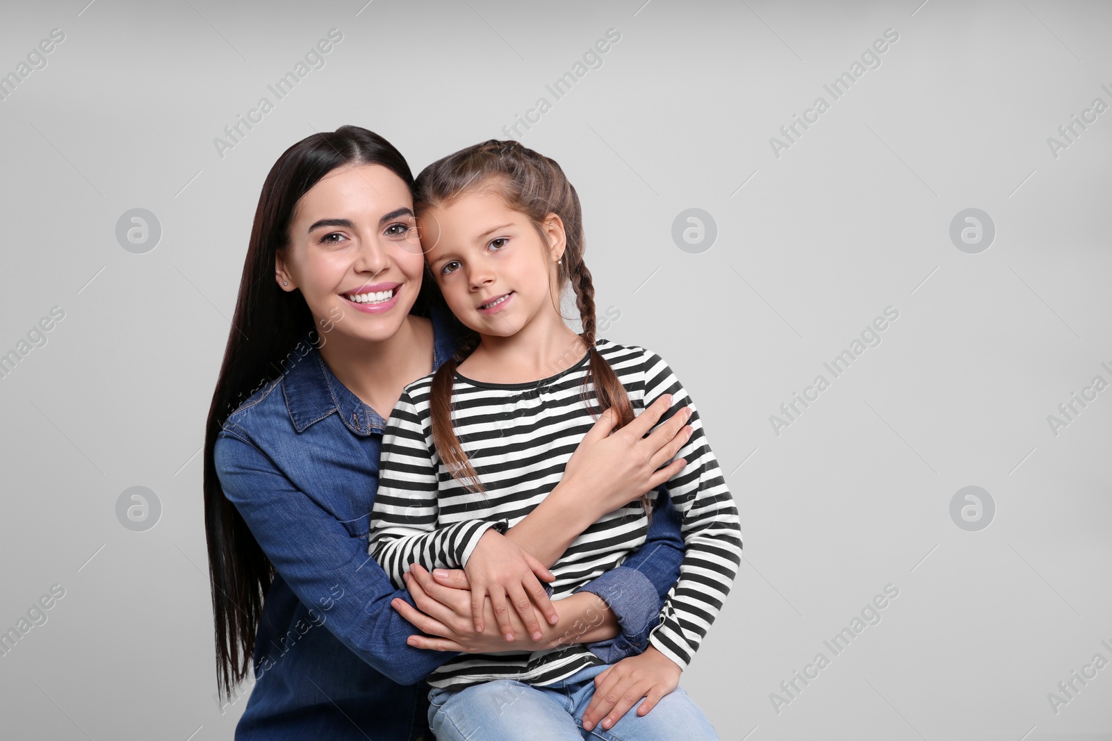 Photo of Happy woman with her cute daughter on light grey background, space for text. Mother's day celebration