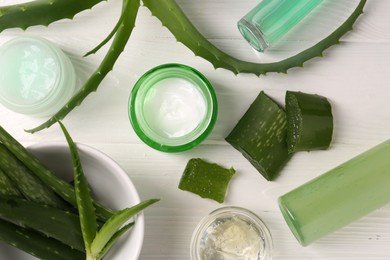 Different cosmetic products and cut aloe vera leaves on white wooden table, flat lay