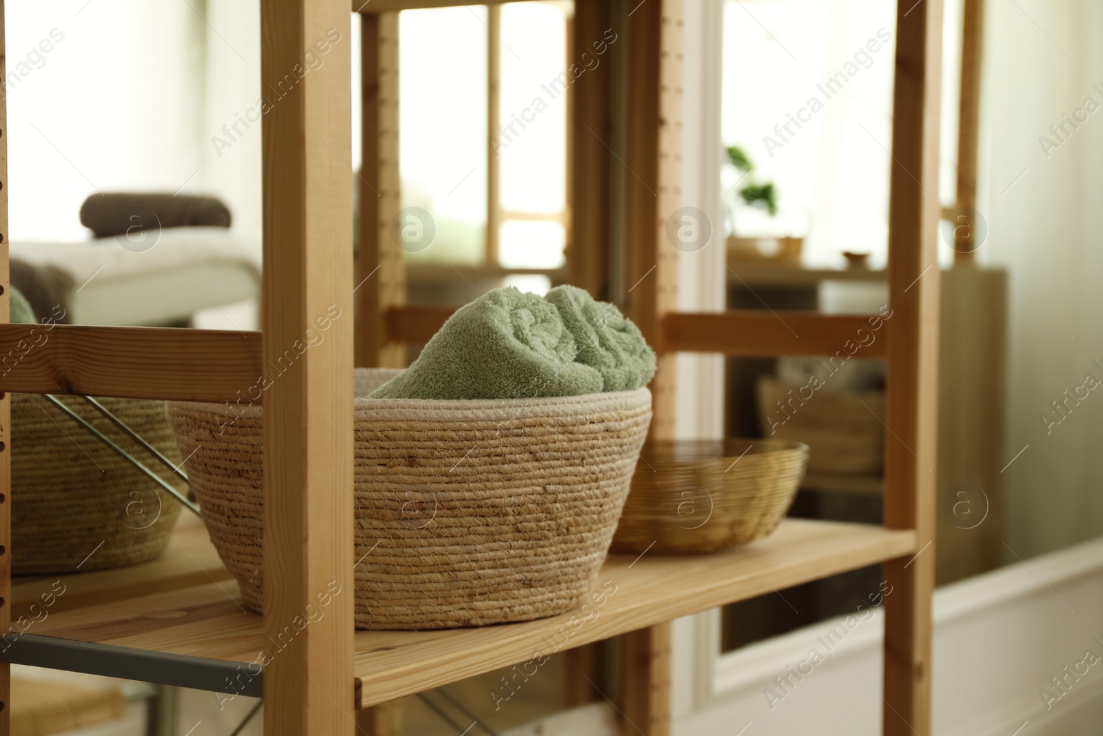 Photo of Wicker basket with soft terry towels on shelving unit in spa salon