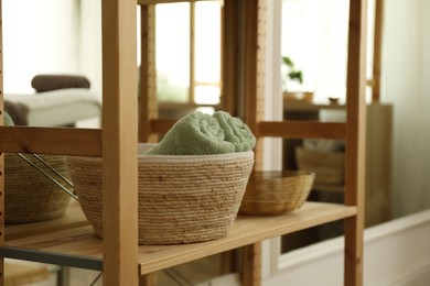 Photo of Wicker basket with soft terry towels on shelving unit in spa salon