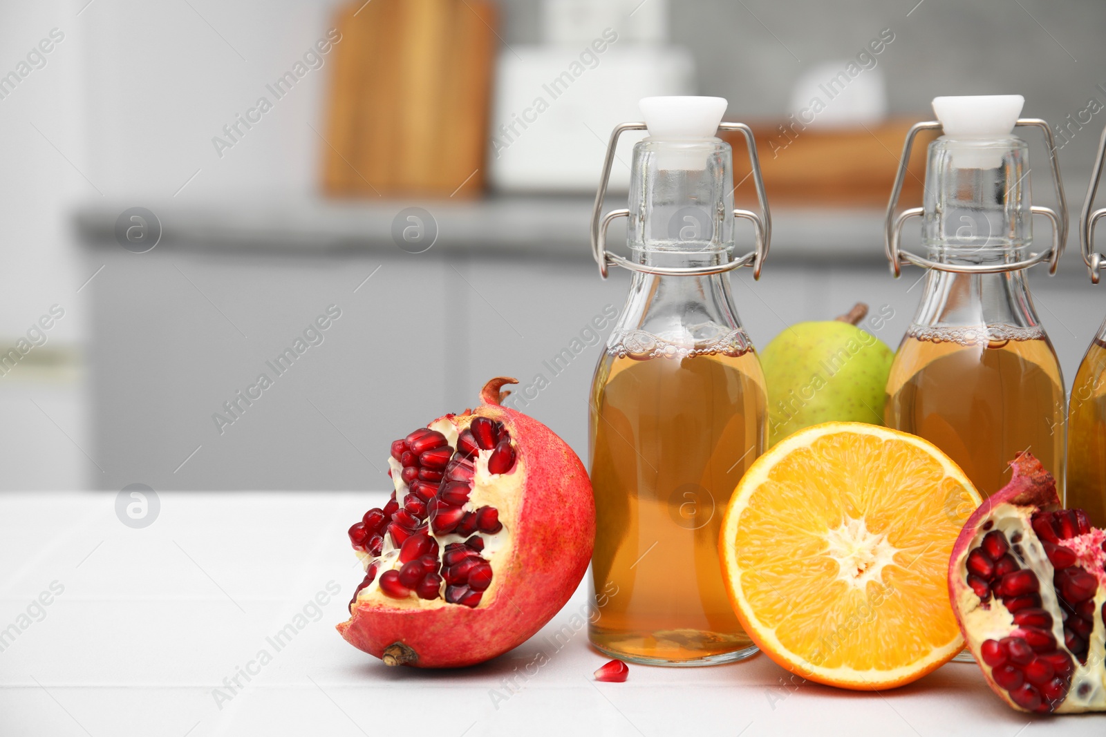 Photo of Homemade fermented kombucha and fresh fruits on white table in kitchen. Space for text