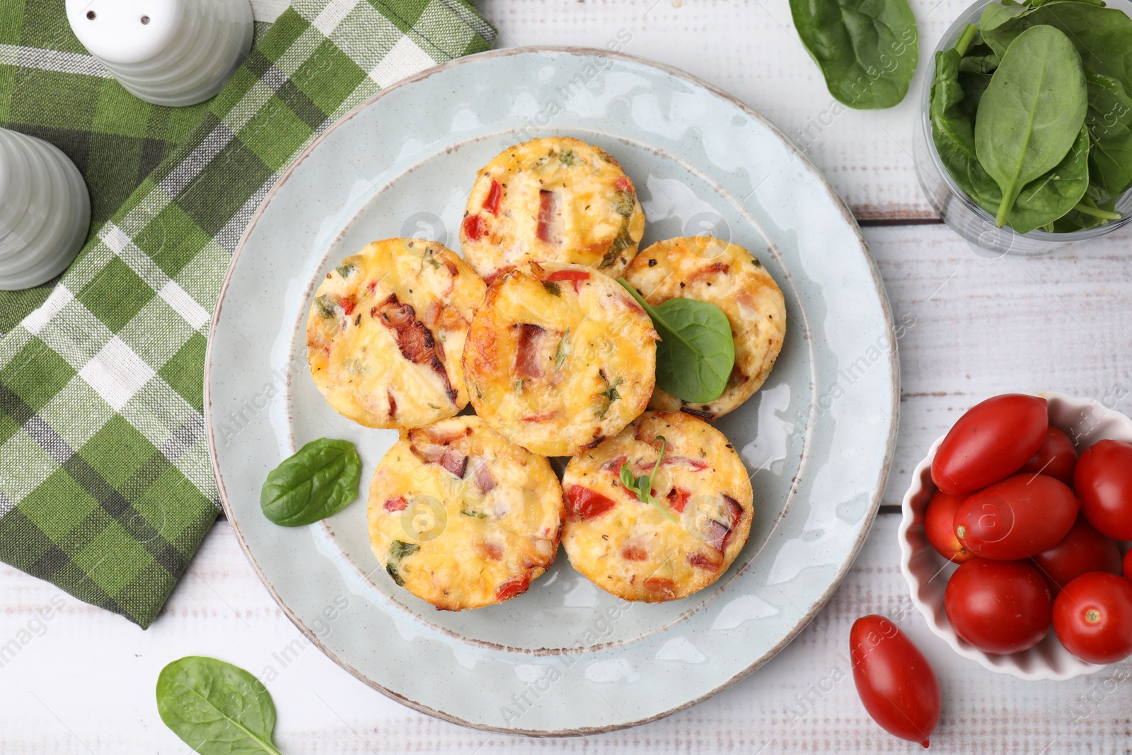 Photo of Delicious egg muffins with cheese and bacon on white wooden table, flat lay