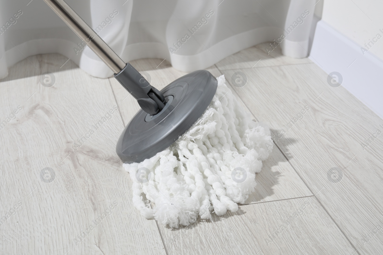 Photo of Cleaning white parquet floor with mop, closeup