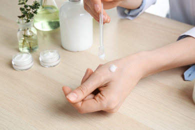Photo of Woman applying natural cream onto hand in cosmetic laboratory, closeup