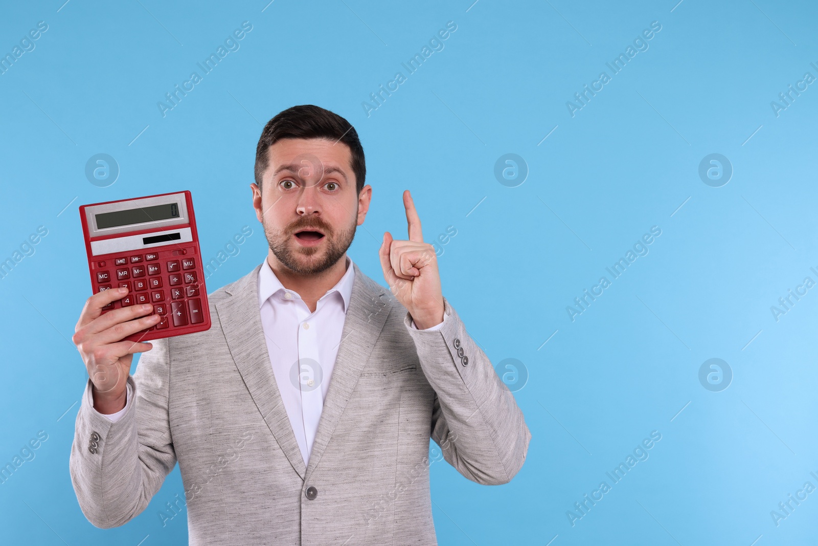 Photo of Emotional accountant with calculator on light blue background. Space for text