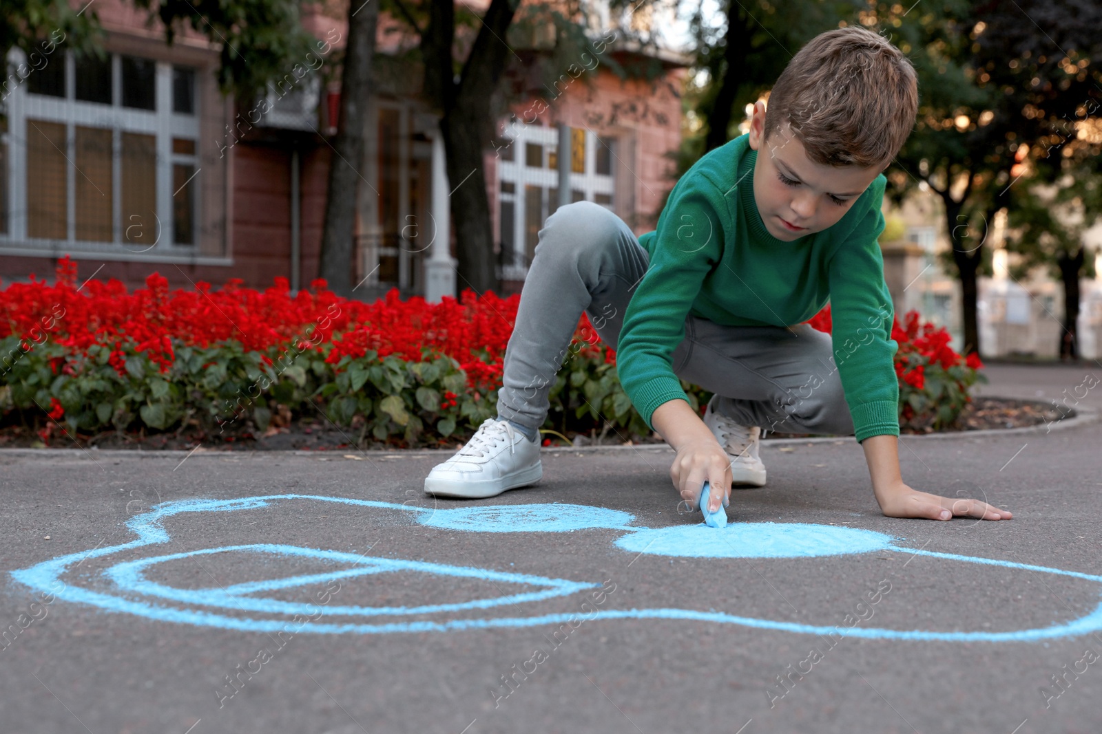 Photo of Child drawing car with chalk on asphalt