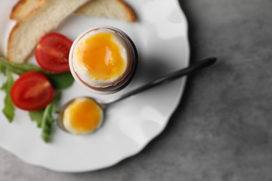 Photo of Breakfast with soft boiled egg on grey table, top view. Space for text