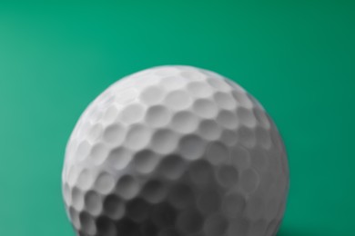 One golf ball on green background, closeup