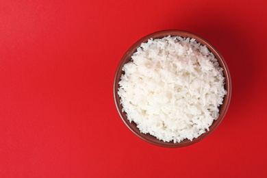 Photo of Bowl of boiled rice on color background, top view with space for text