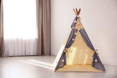 Photo of Cozy play tent for kids as element of nursery interior in empty room with space for text