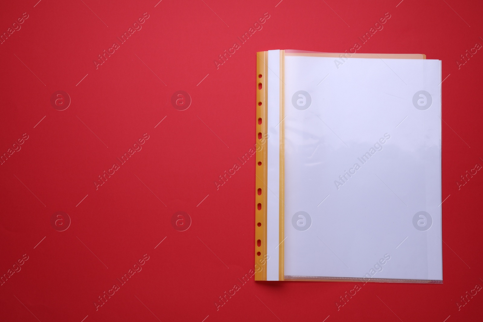 Photo of File folder with punched pockets and paper sheets on red background, top view. Space for text