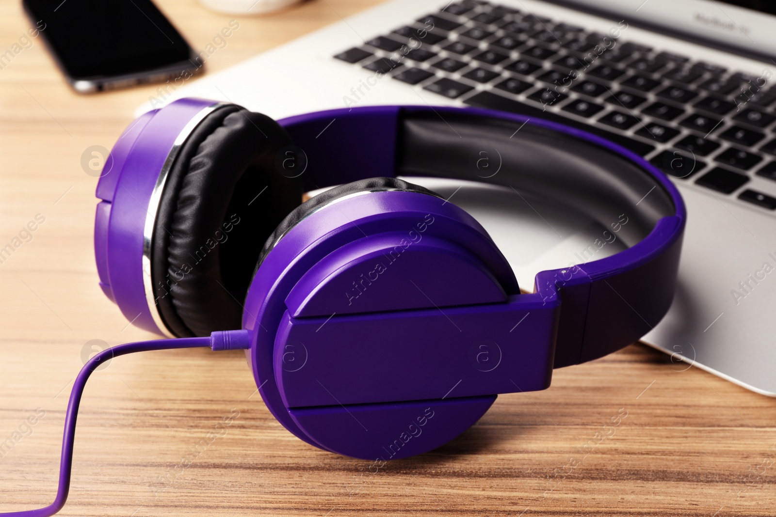 Photo of Modern headphones and laptop on table, closeup